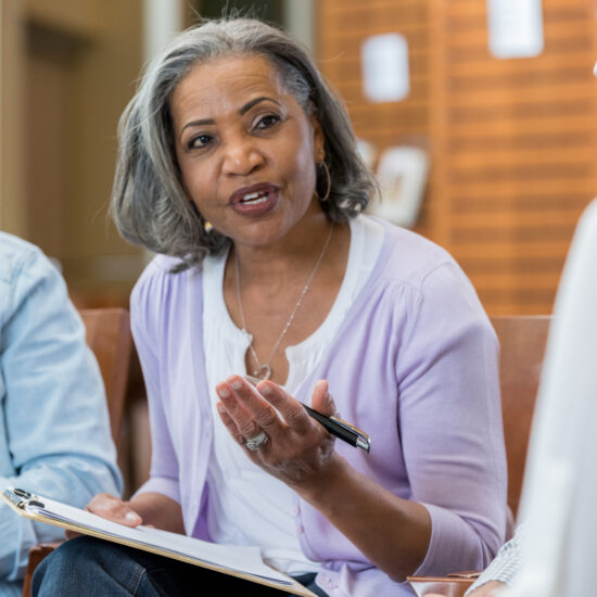 Confident senior African American female therapist discusses something during a support group meeting.