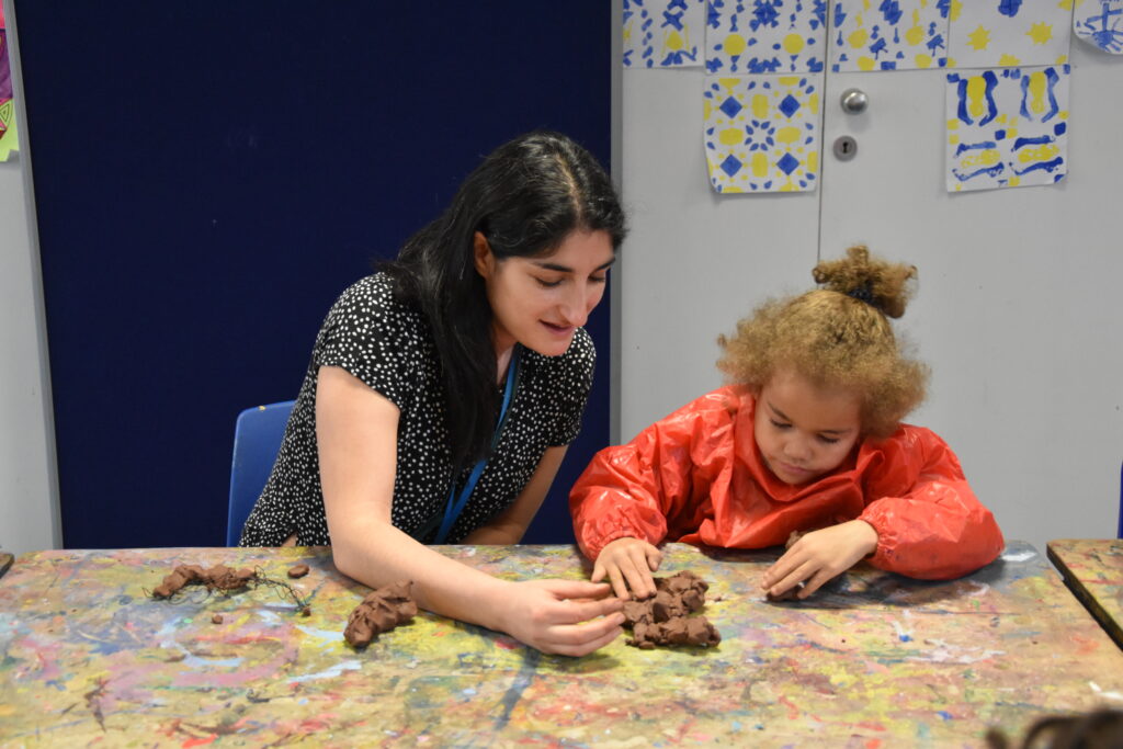 Adult and child at a table playing with clay