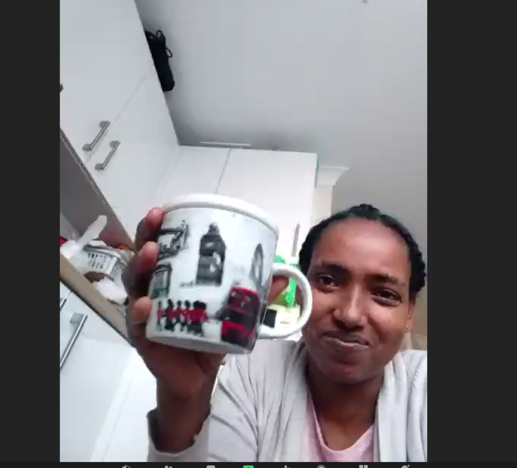 Woman holding a mug up to the screen.,