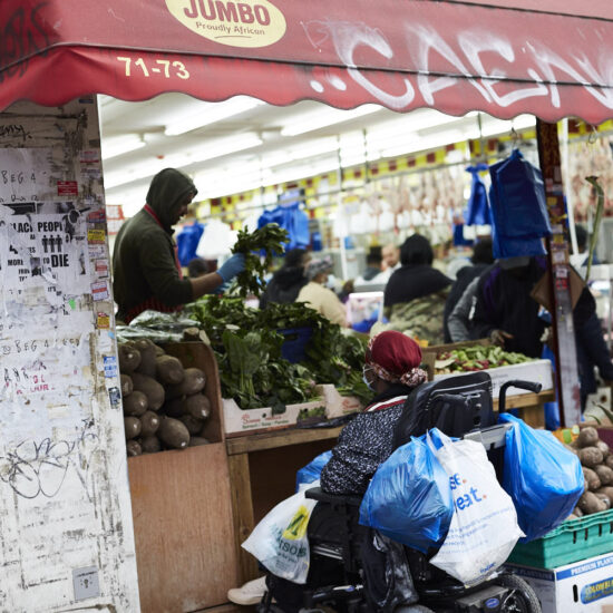 Busy shopfront, featuring woman in wheelchair, wearing a mask with lots of shopping bags