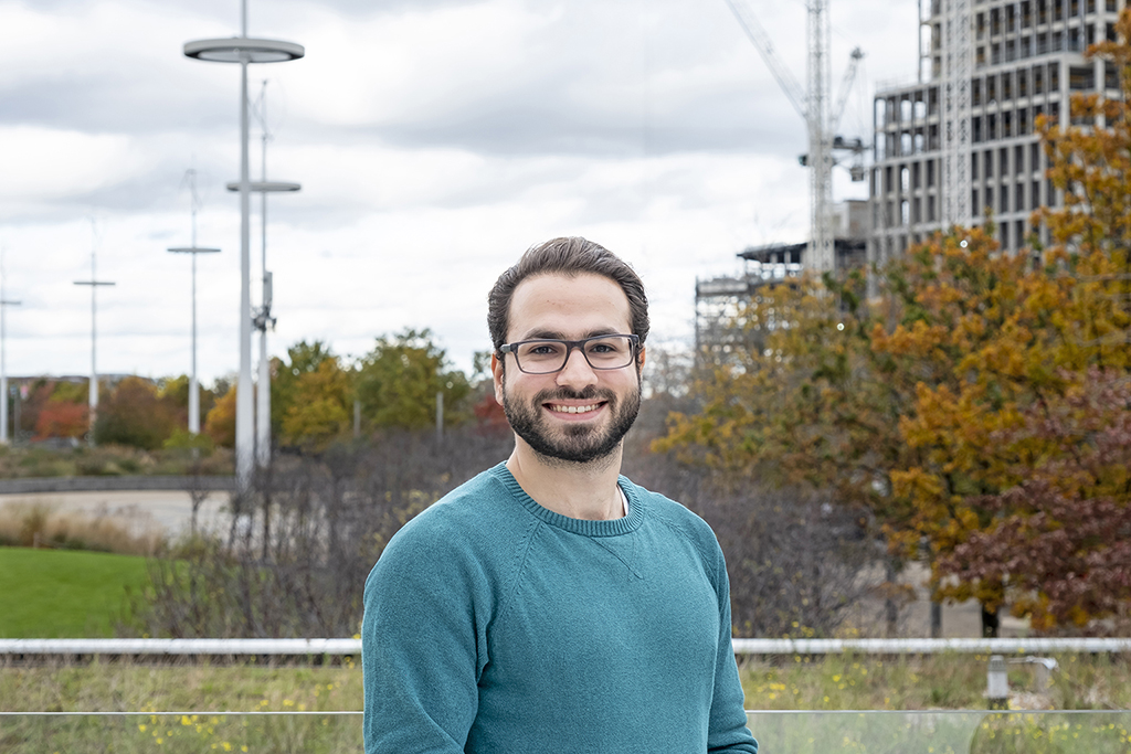 Mahdy Alraie smiling at the camera with Autumnal trees in the background.