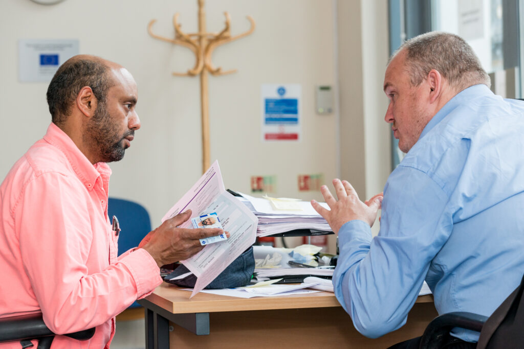 two men sitting at a desk in conversation