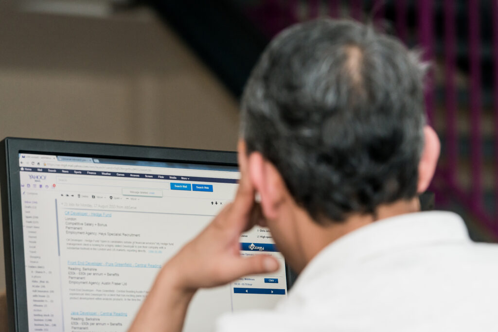 Back of man's head. He's looking at a computer screen.
