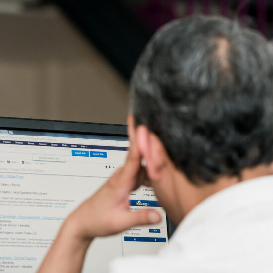 Back of man's head. He's looking at a computer screen.