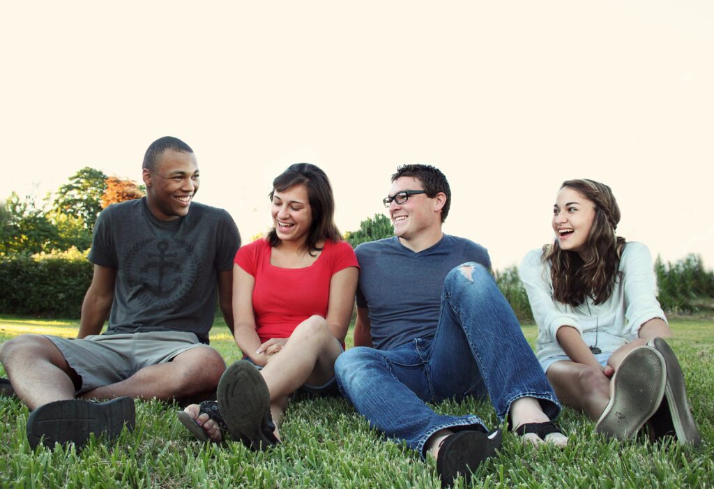 4 young people sitting outside on the grass.