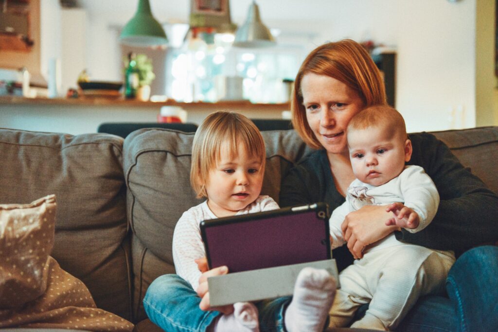 Parent with 2 children on her lap holding an ipad