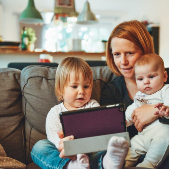 Parent with 2 children on her lap holding an ipad
