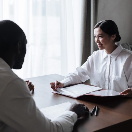 Asian Social Worke sitting at a table facing a couple. There is an open folder on the table.