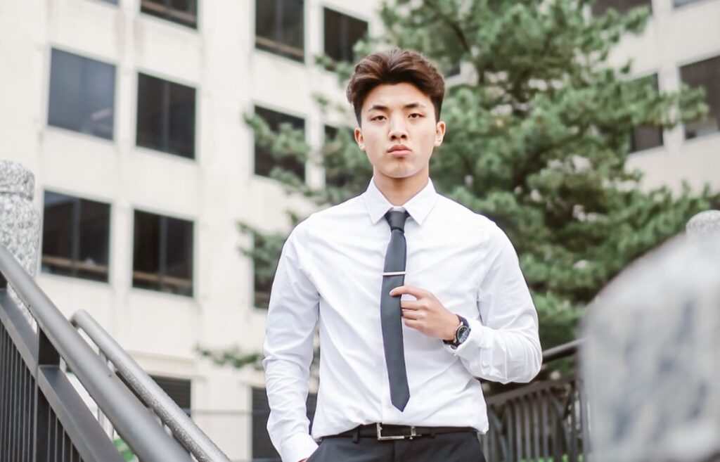 A young Asian man in a shirt and tie looking determinedly into the distance.
