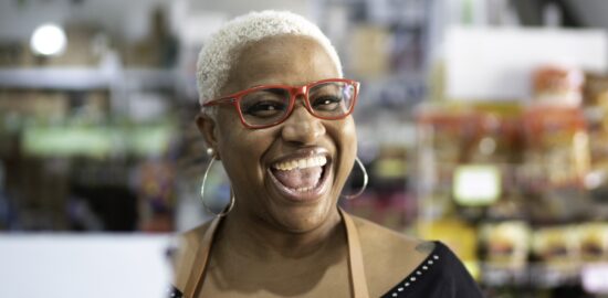 Happy cashier wearing bright glasses and an apron.
