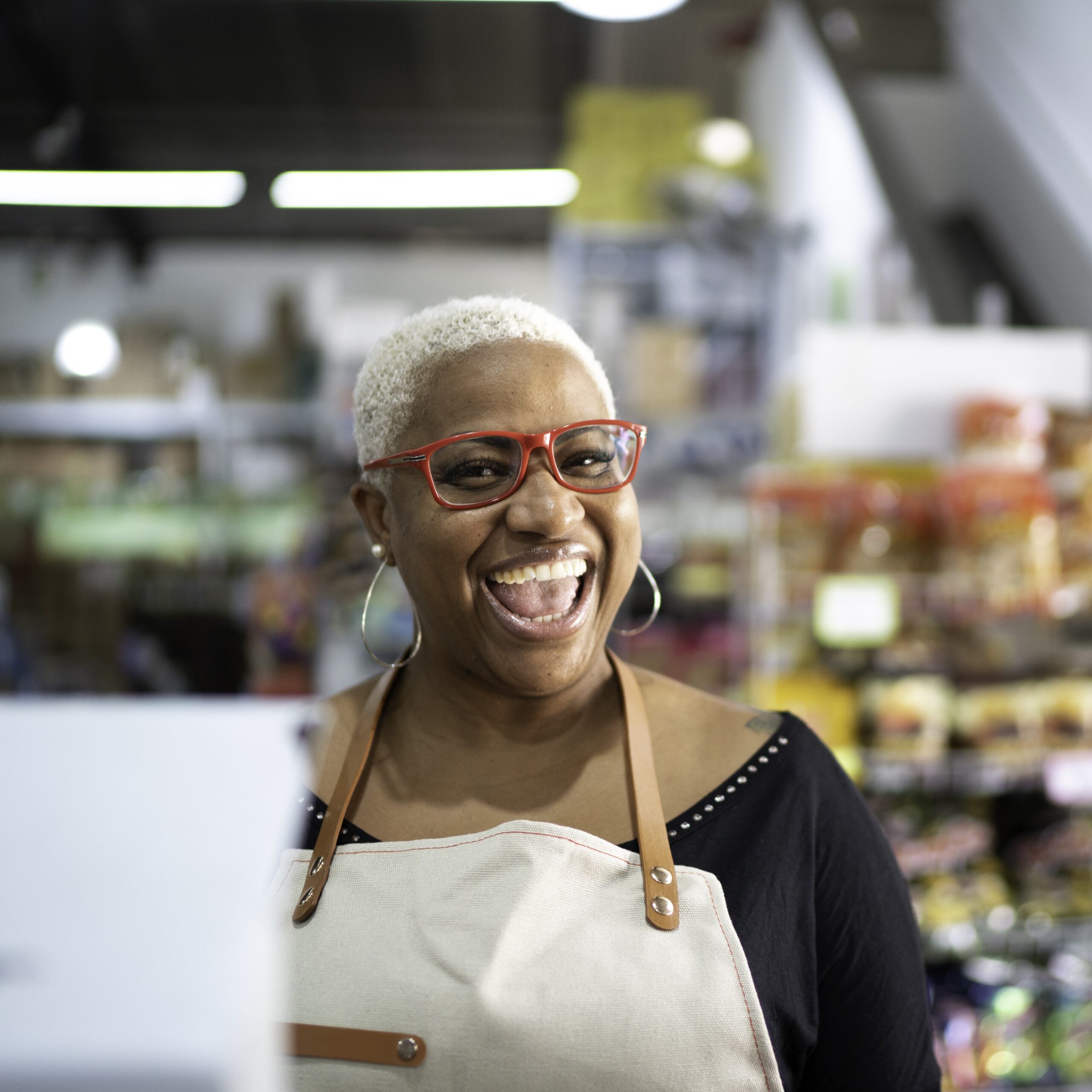 Happy cashier wearing bright glasses and an apron.