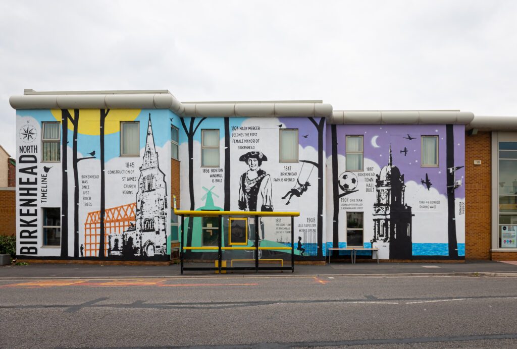 A mural on the side of a building depicting the history of Birkenhead. It says Birkenhead was once all birch trees.